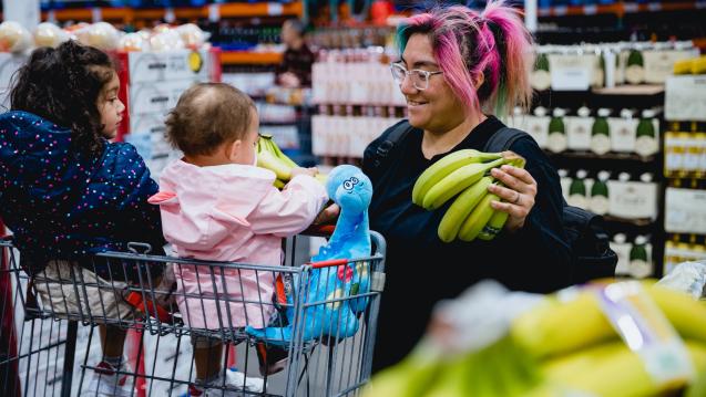 Women in a grocery store with 2 kids, holding bananas
