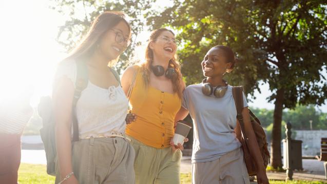 three young women walking together happily