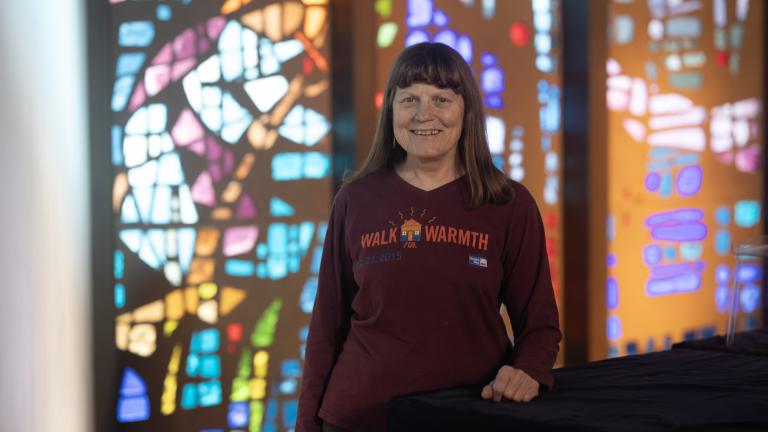 Woman standing in a red shirt that reads "Walk for Warmth"