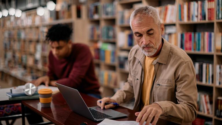 Man working with a computer and a manual